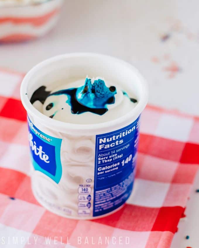 Drops of blue food coloring added to a tub of white frosting.  