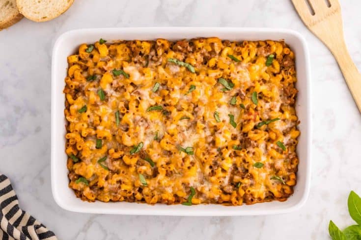 Cheesy beef zucchini macaroni bake in a white casserole dish on a marble counter. 
