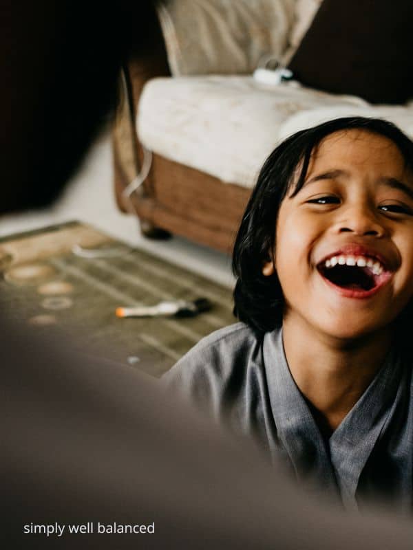 A boy laughing at a funny word during a game of hangman.