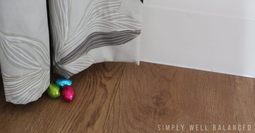 Plastic Easter Eggs hidden indoors behind a long curtain. 
