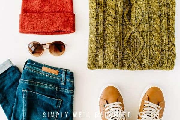 The perfect Fall Capsule Wardrobe Items - jeans, a cable knit sweater, sunglasses, a hat, and casual sneakers. 