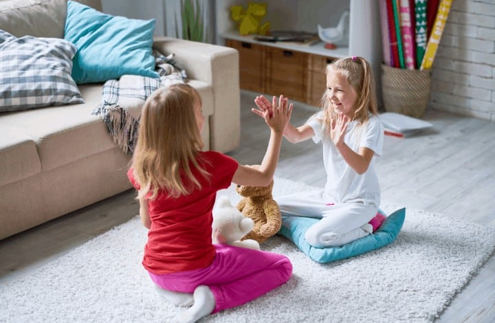 Kids playing hand clapping games on living room floor