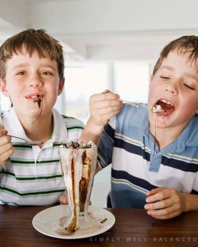 Two boys eating ice cream sundaes that they made at a sleepover. 