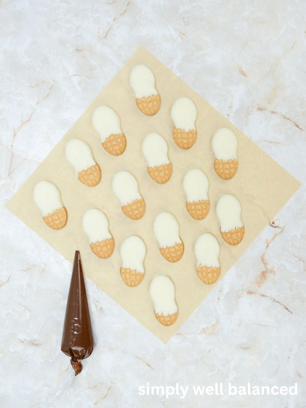 Nutter Butter Cookies dipped in white chocolate on a piece of parchment paper. 